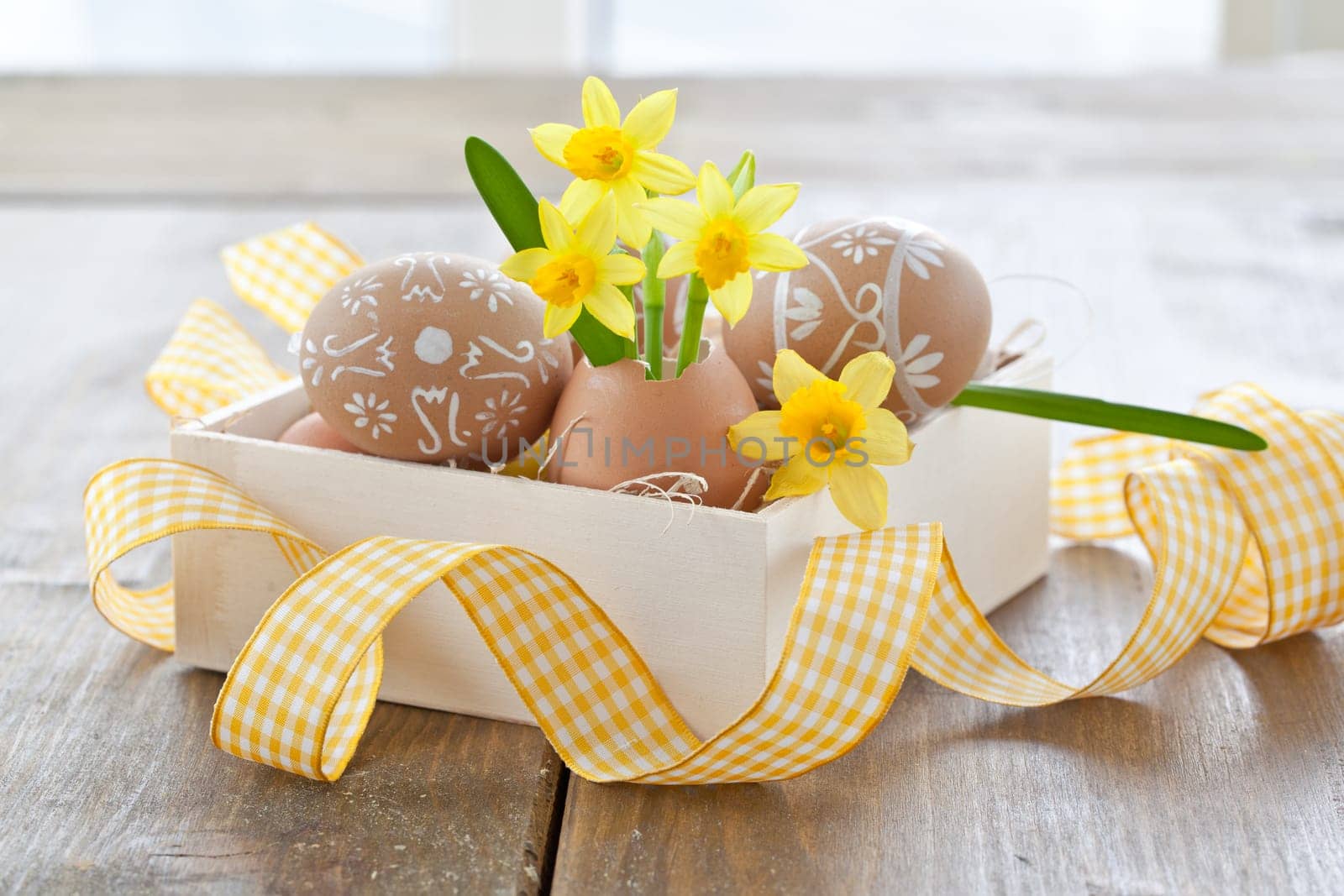 Fresh daffodils in eggshell and painted Easter eggs