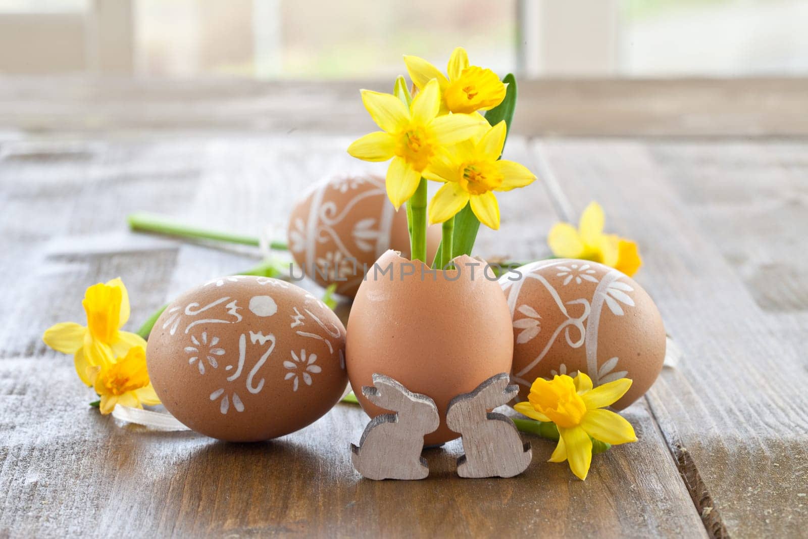 Fresh daffodils in eggshell and painted Easter eggs