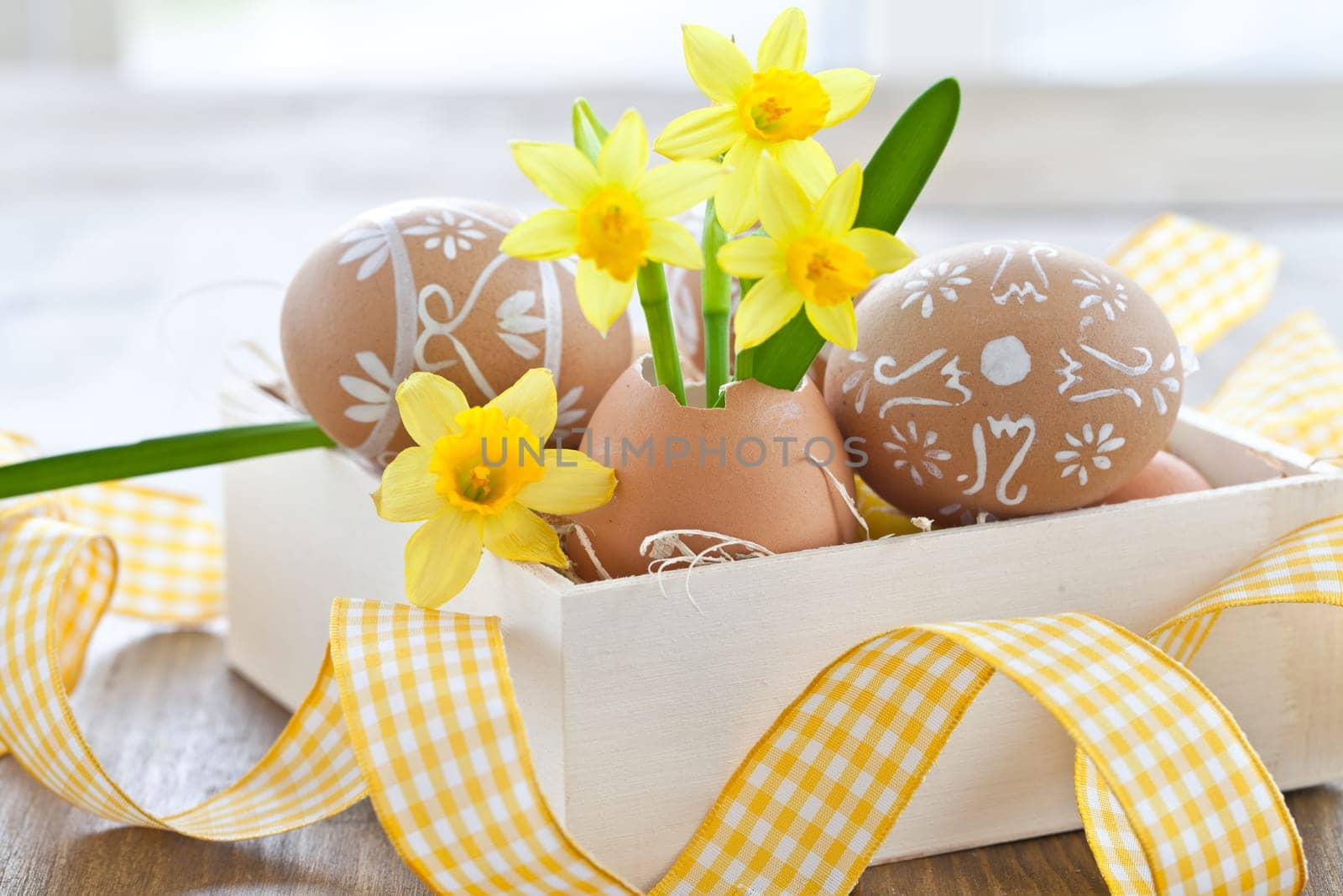 Fresh daffodils in eggshell and painted Easter eggs