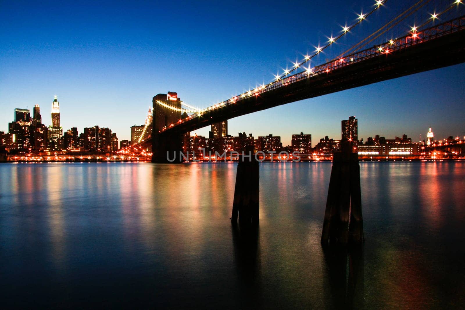 New York City Manhattan skyline panorama with Brooklyn Bridge and office skyscrapers building in at dusk illuminated with lights at night