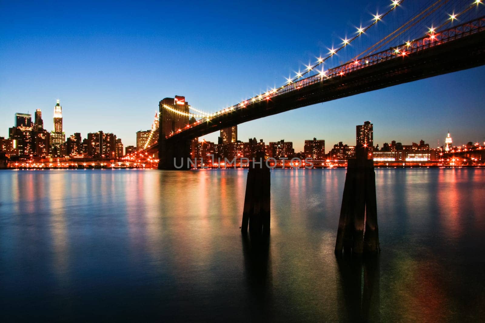 New York City Manhattan skyline with Brooklyn Bridge and office skyscrapers building in at dusk illuminated with lights at night
