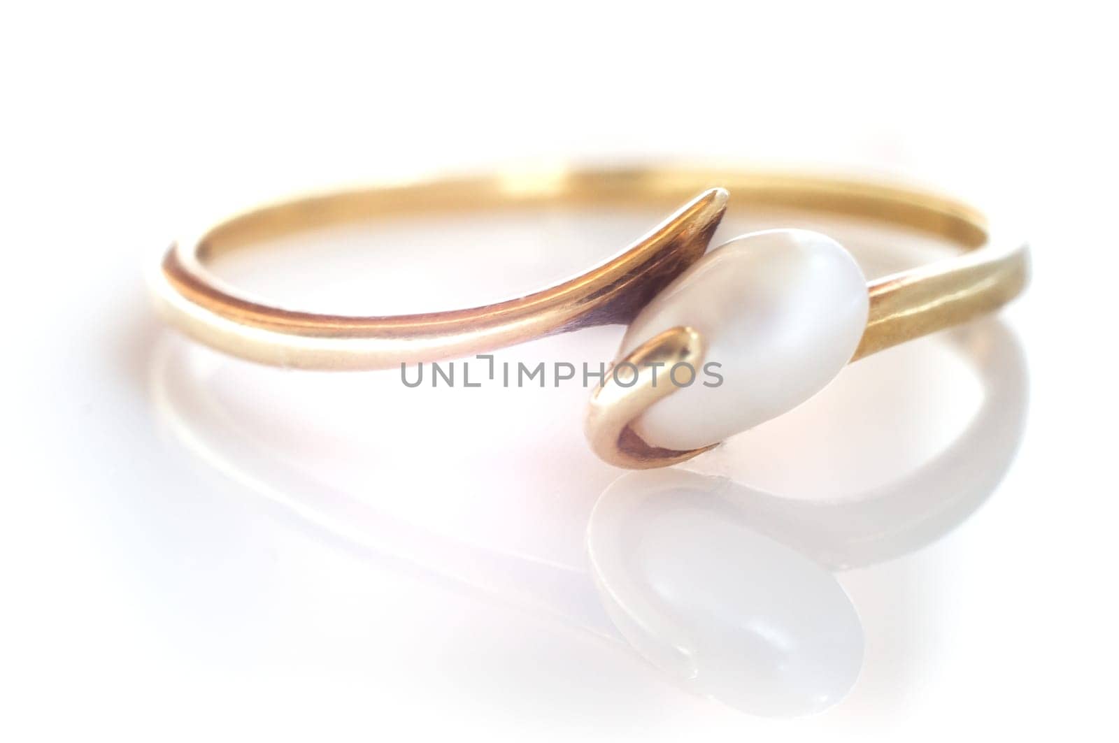Macro shot of a golden pearl ring on a white background - with reflection.