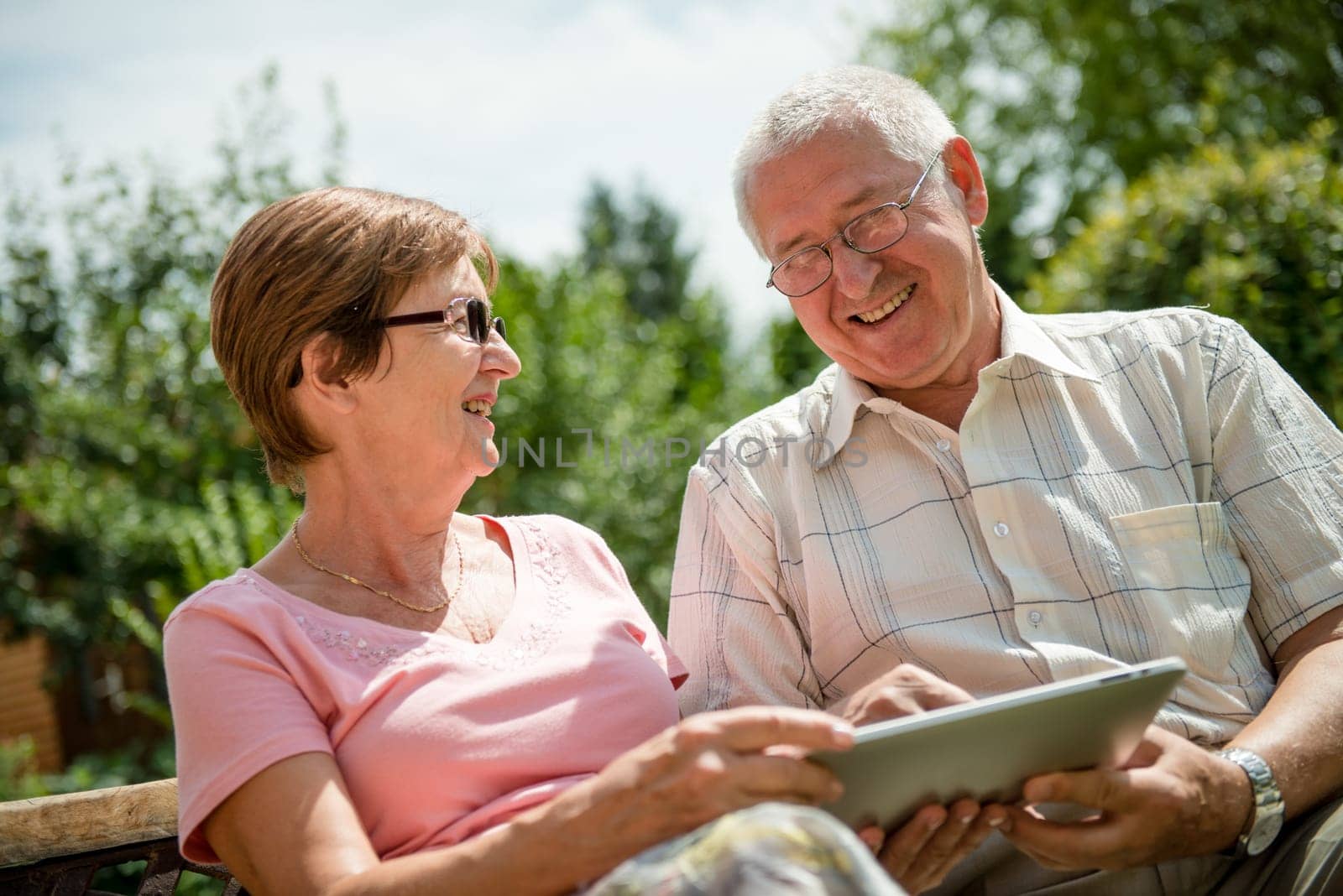 Lifestyle portrait of smiling happy senior couple working with tablet - outdoor