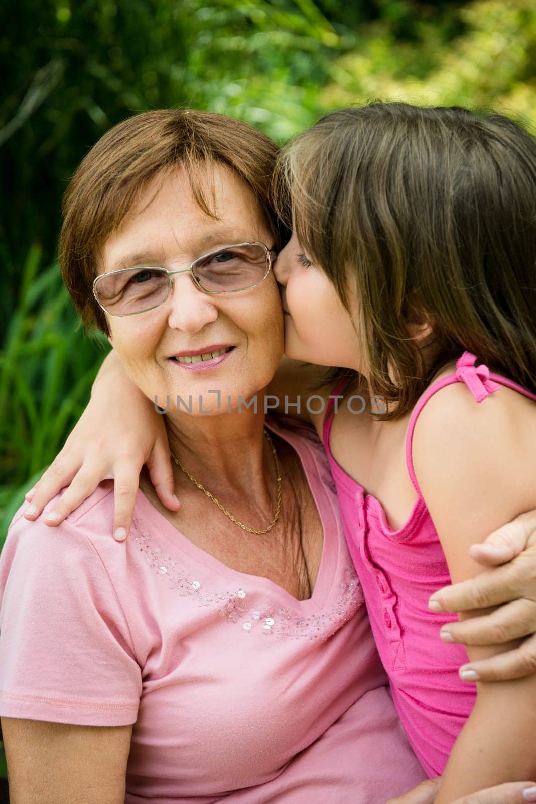 Lifestyle portrait of grandchild kissing grandmother - outdoor in nature