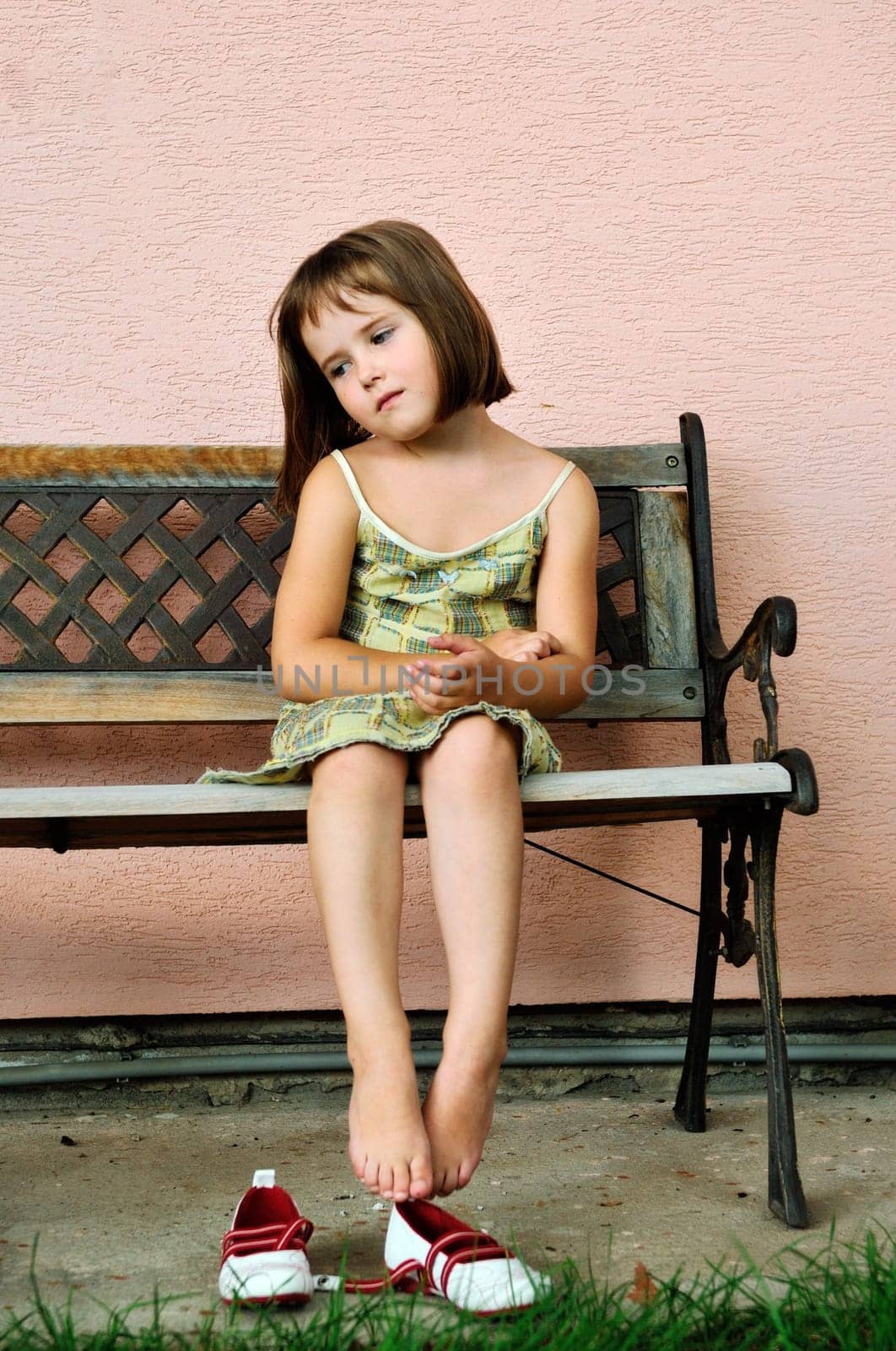 Sad girl - outdoor portrait of small cute child sitting on bench