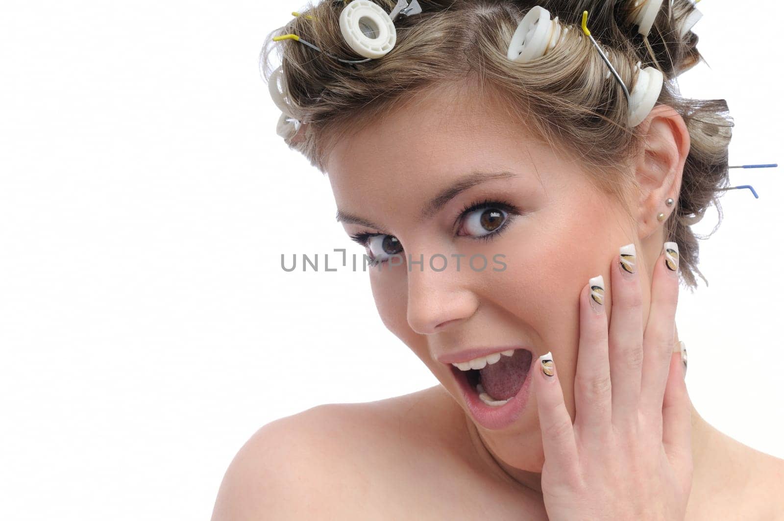 Young beautiful surprised woman with hair rollers in curls isolated on white