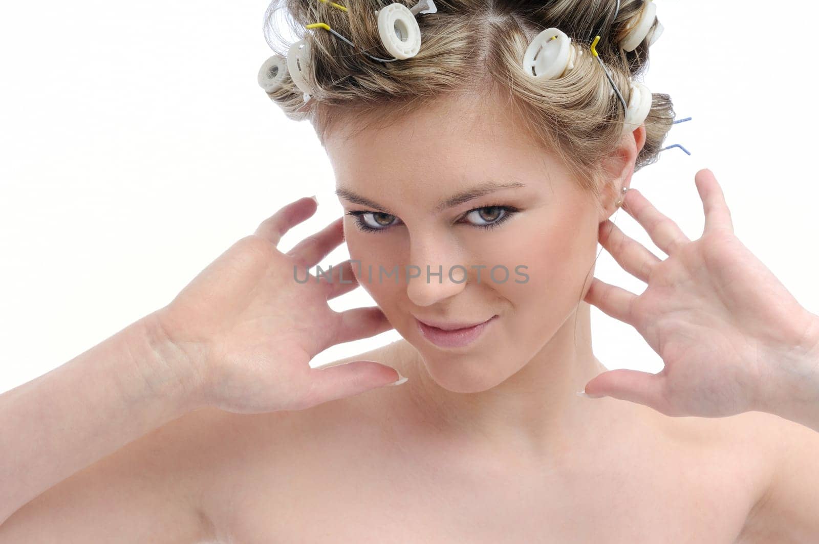 Young beautiful woman with hair curlers pretending to listen isolated on white