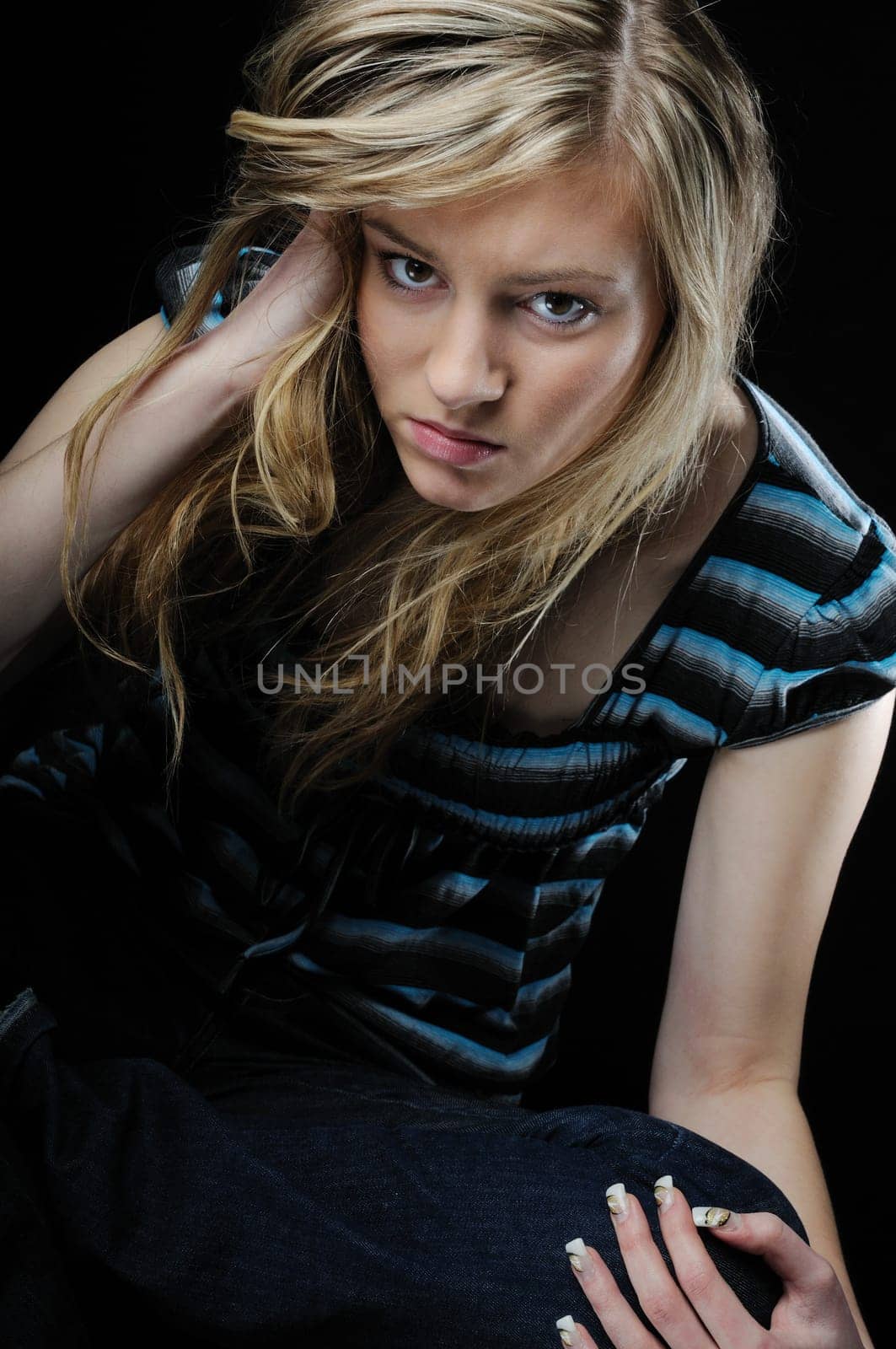 Young beautiful blond depressed woman (teenager)isolated on black background