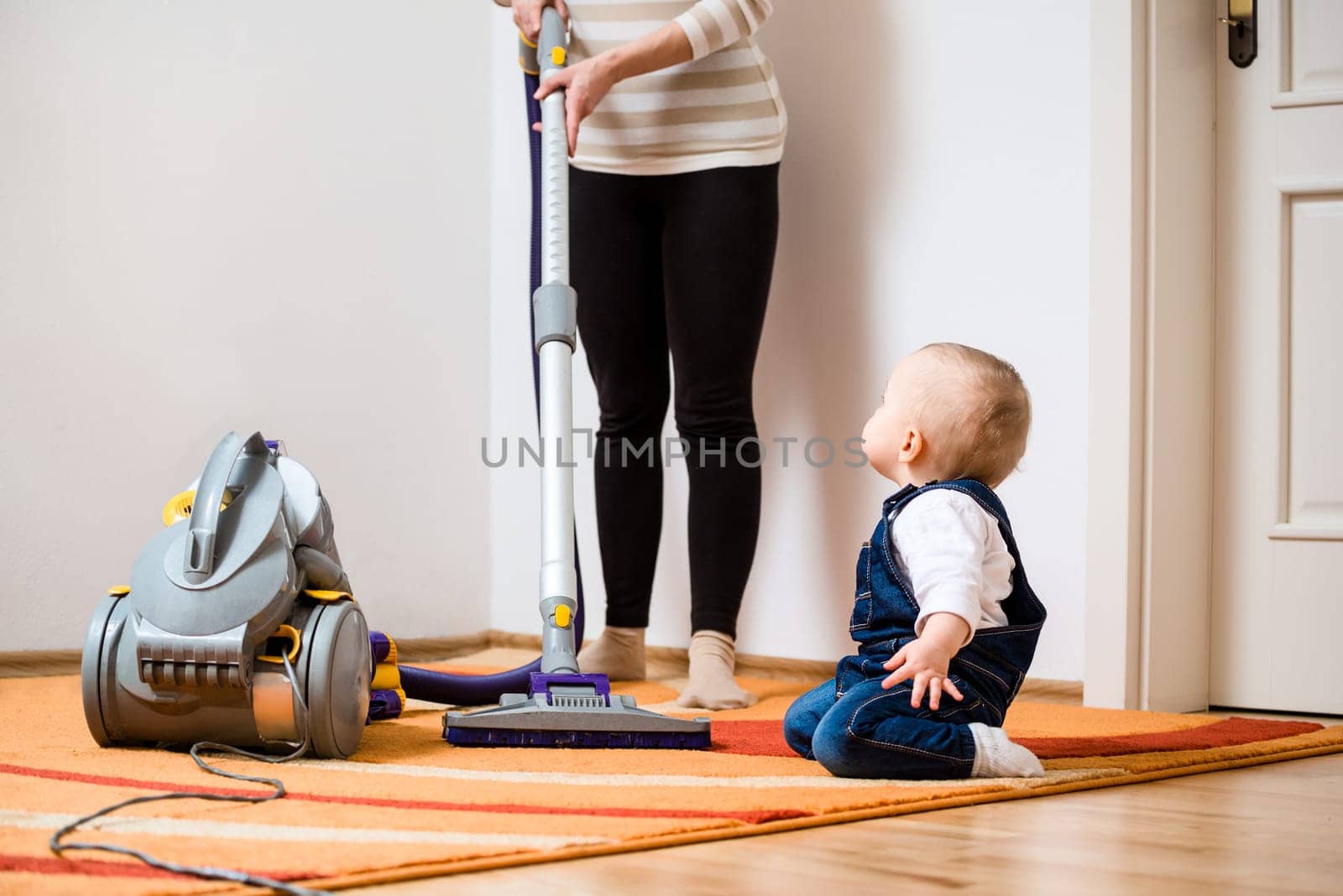 Cleaning up the room together - mother and her baby  with vacuum cleaner