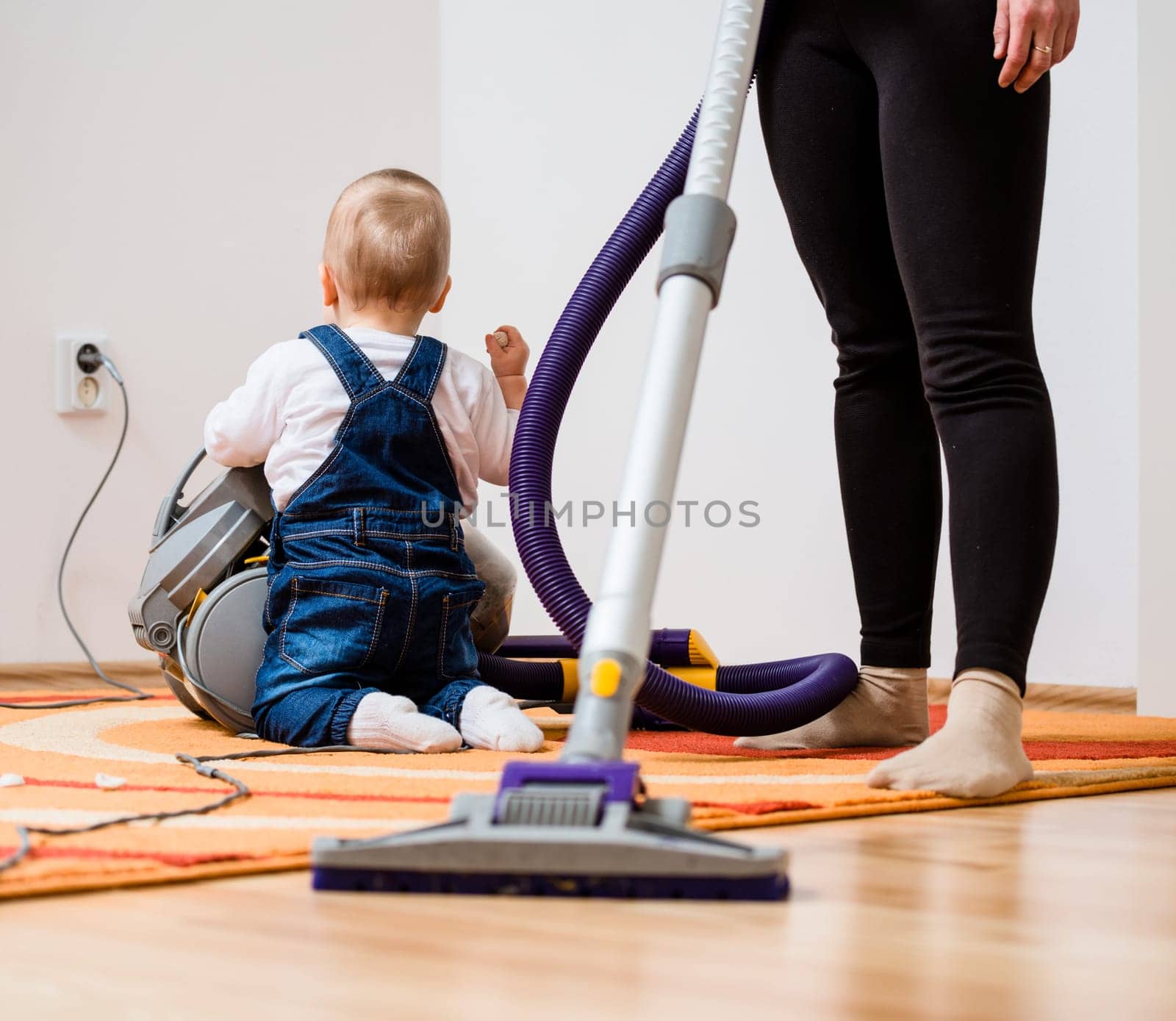 Cleaning up the room - mother and her baby  with vacuum cleaner