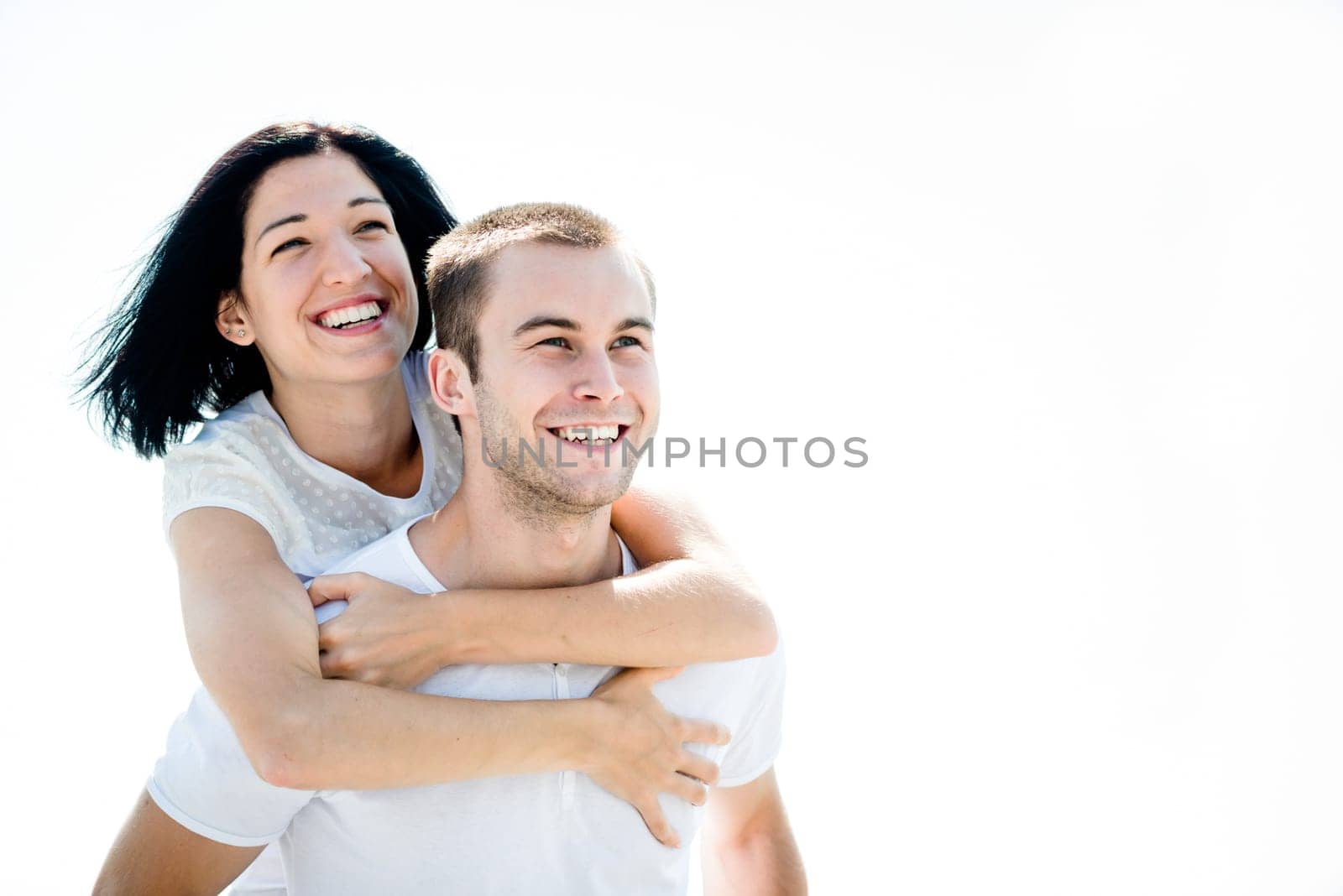 Happy young couple - smiling woman embbracing her boyfriend around neck
