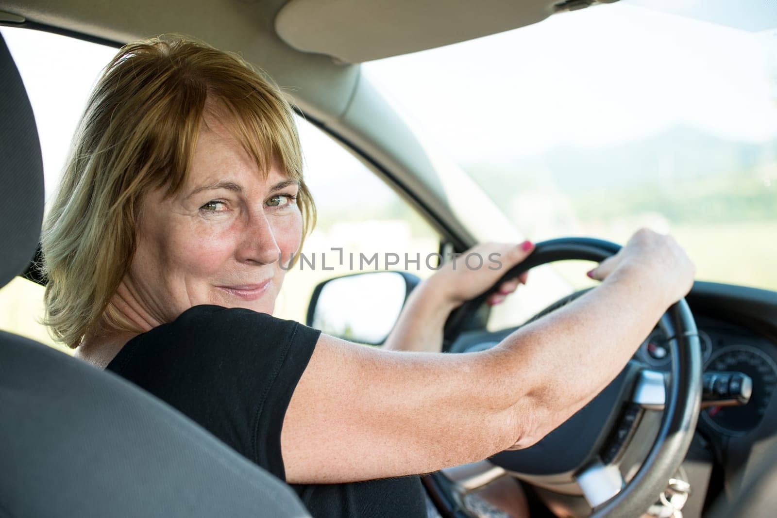 Lifestyle photo of attractive senior woman in car