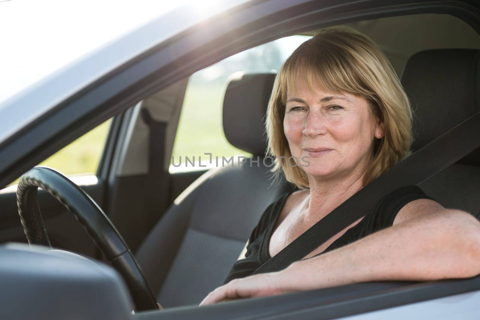Portrait of attractive senior smiling woman sitting in car