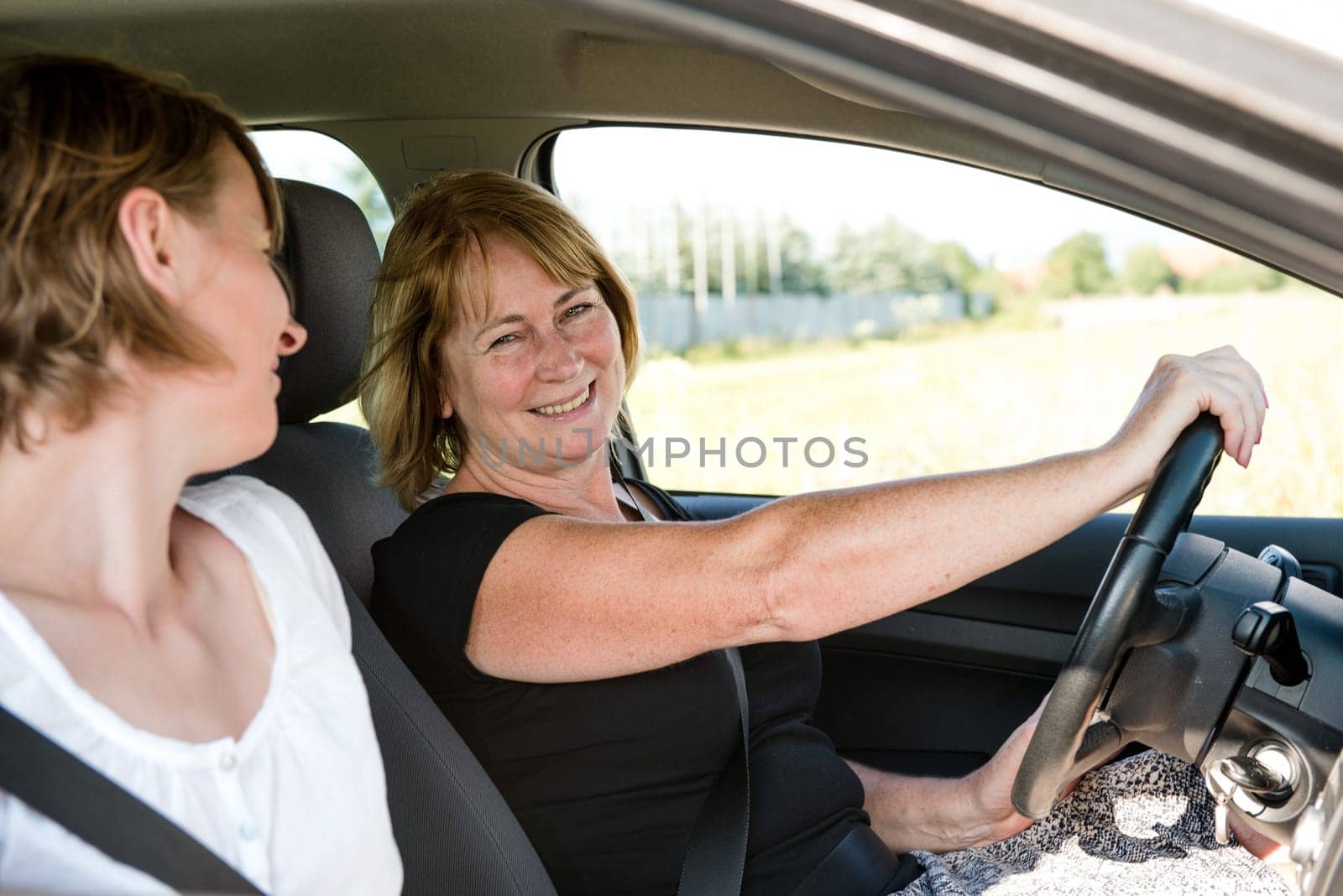Smiling senior woman driving car with her adult child