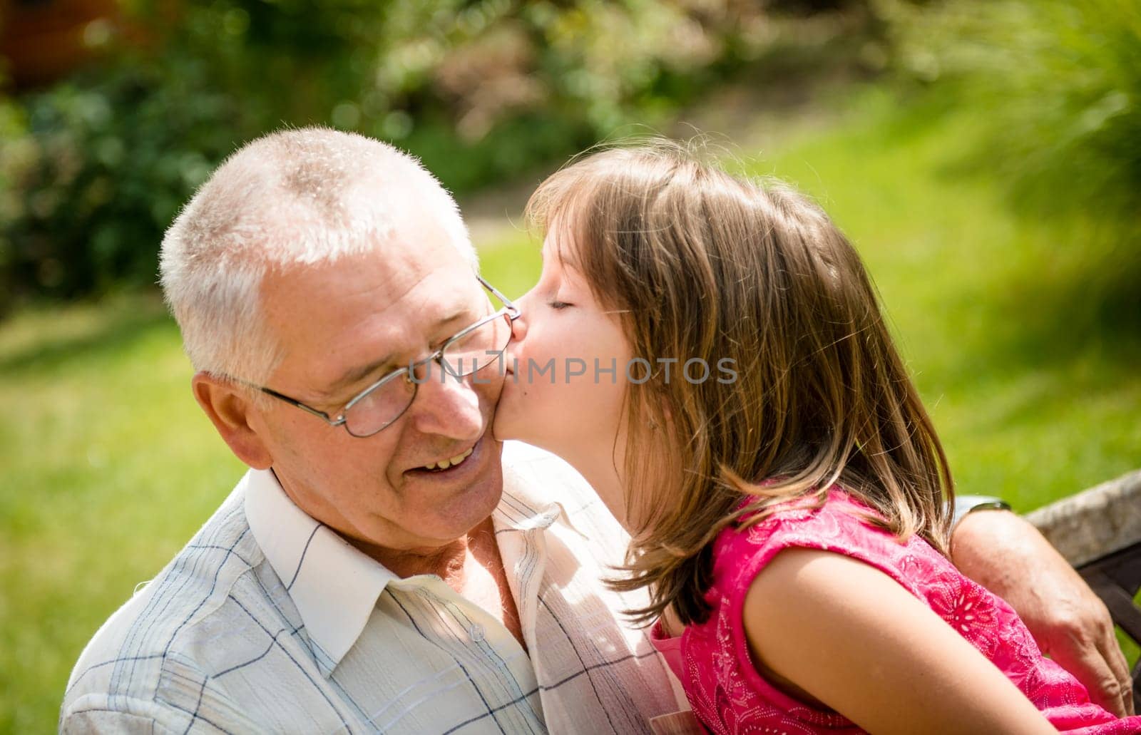 Lifestyle portrait of grandchild kissing grandfather - outside in nature