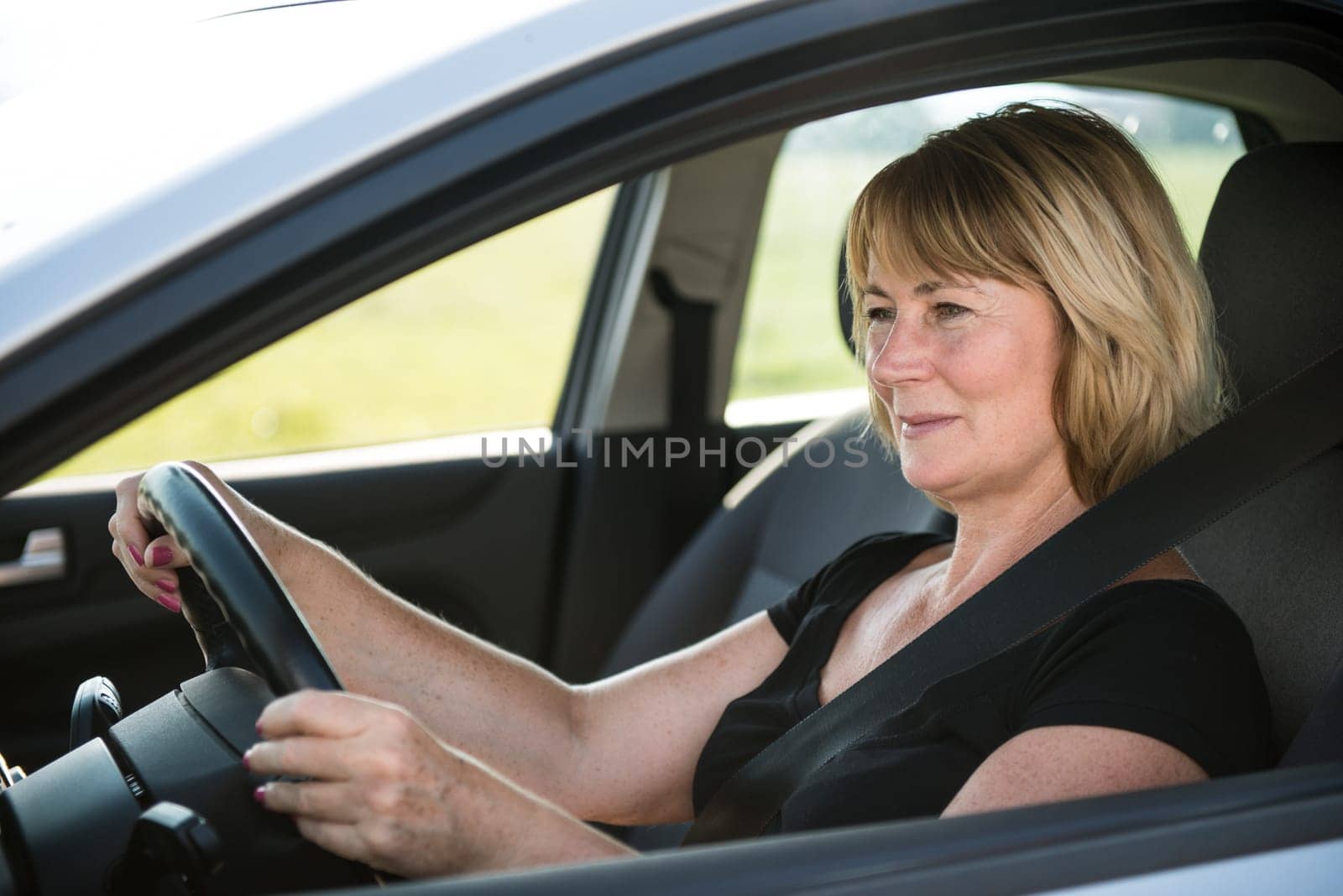 Lifestyle photo of attractive mature woman driving car