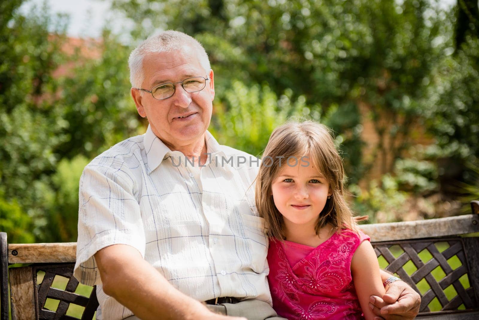Outdoor portrait of grandchild embracing grandfather
