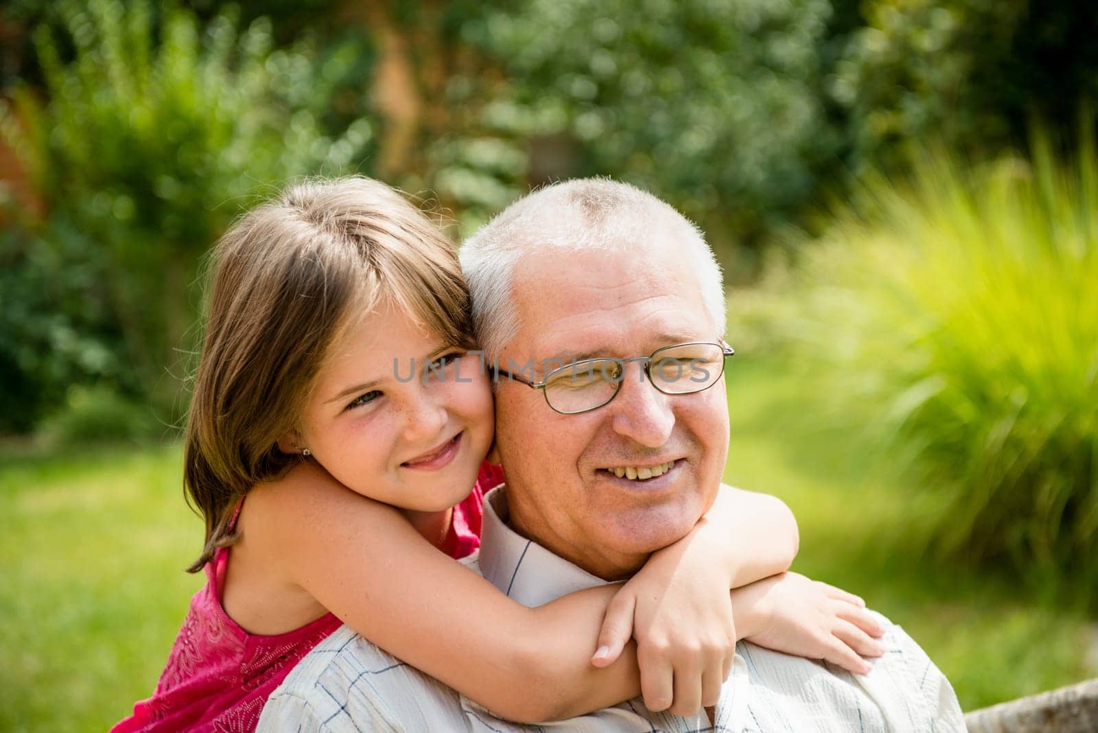 Outdoor lifestyle portrait of grandchild hugging grandfather