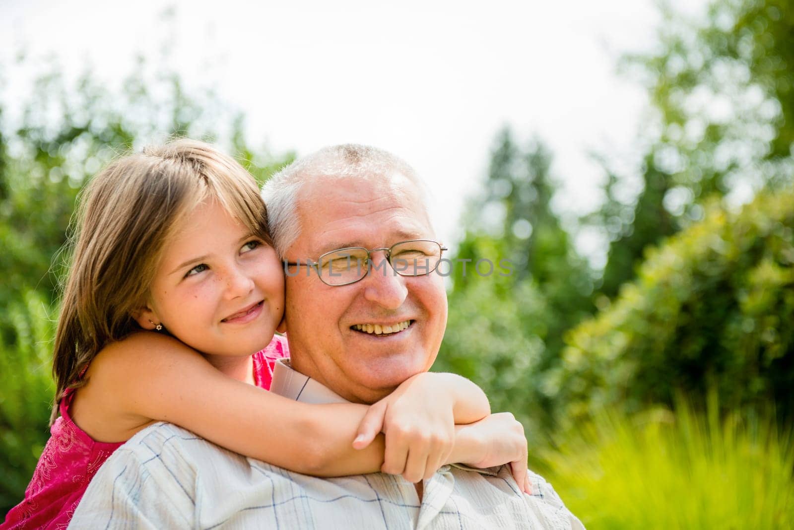 Outdoor lifestyle portrait of grandchild embracing grandfather
