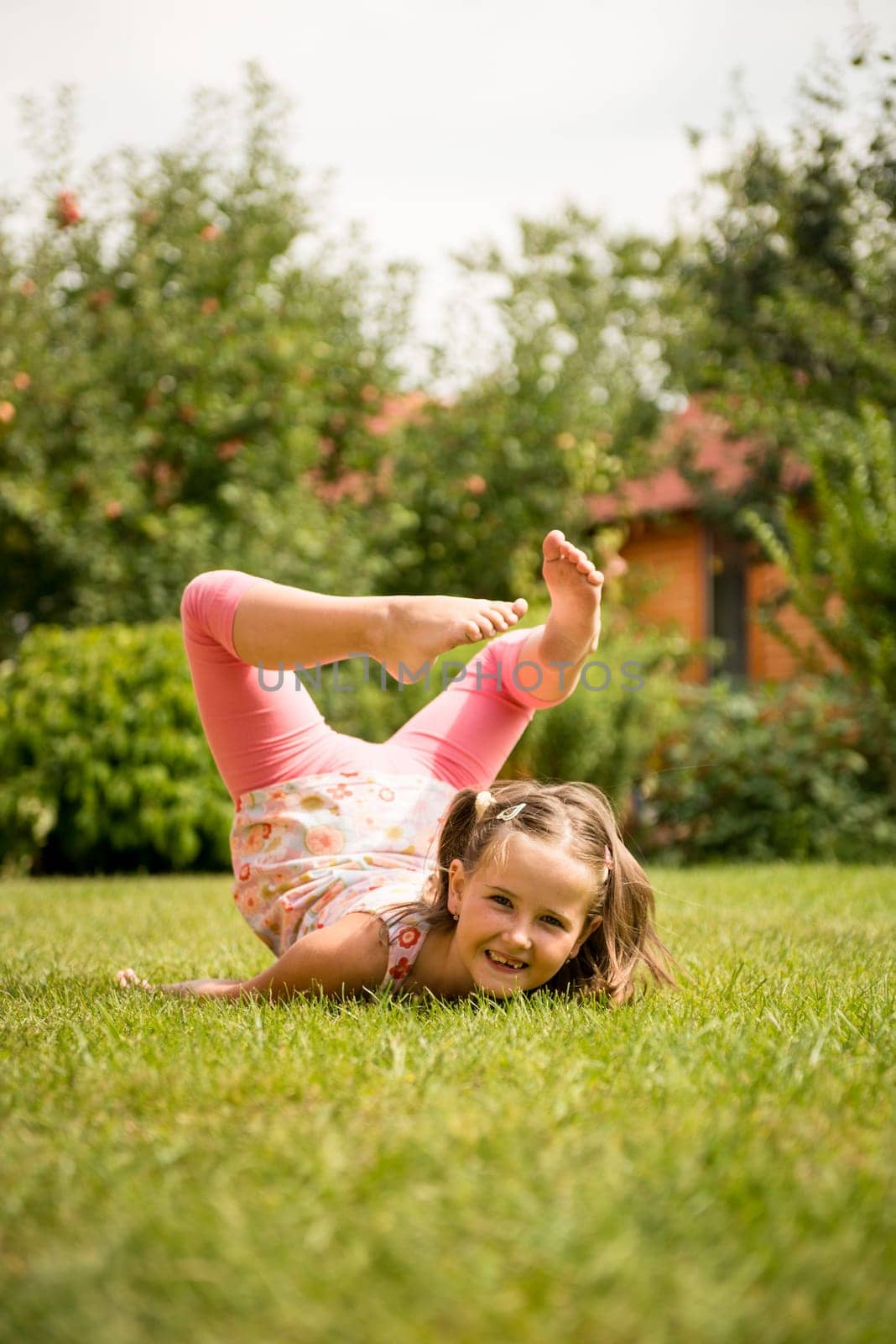 Smiling little child having fun lying on grass - outdoor in backyard