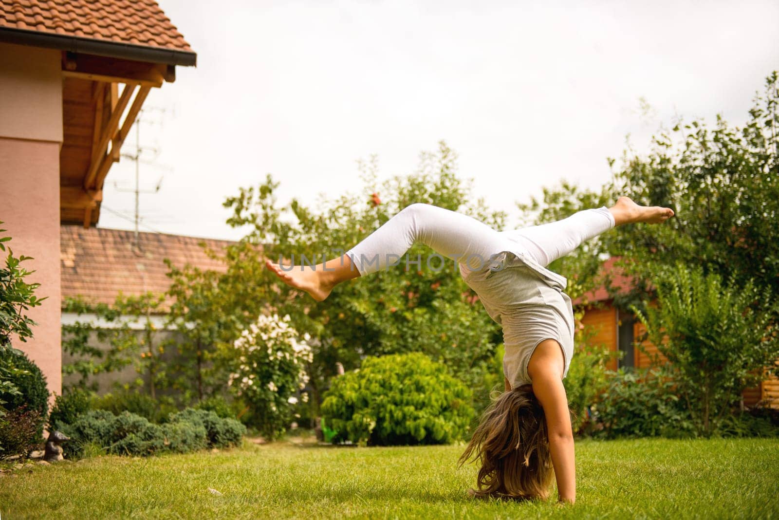 Active childhood - little child making handstand outside in backyard