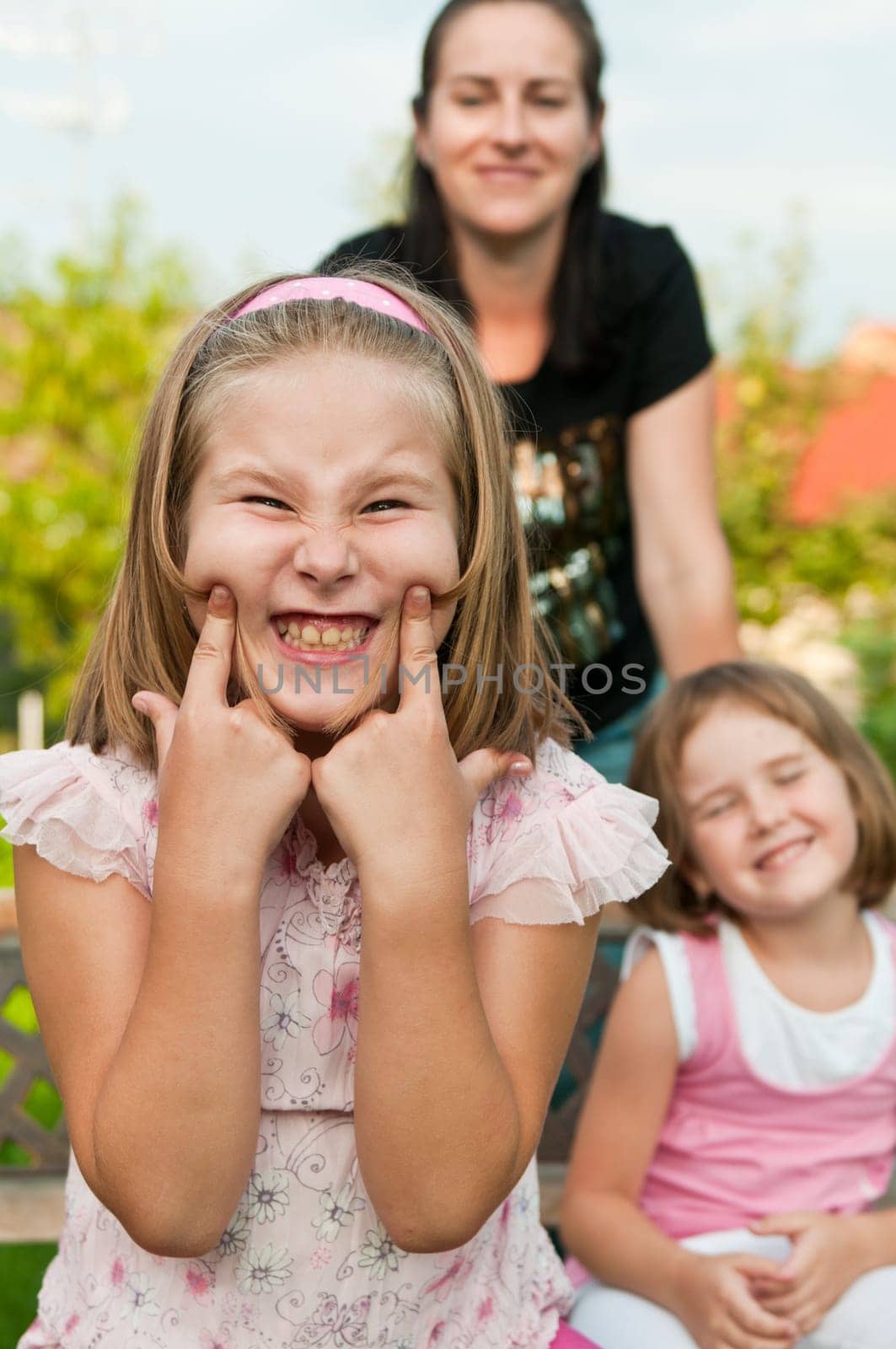 Child with cheeke expression - mother and sister in background