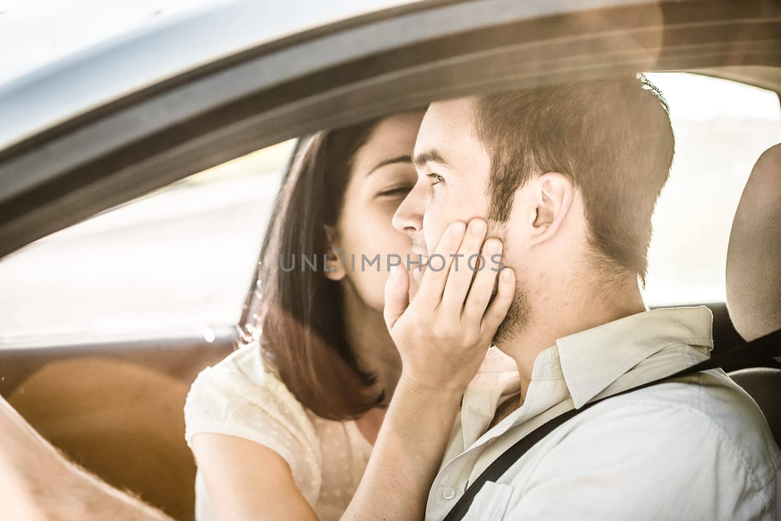 Couple in love - woman kissing man in car while driving