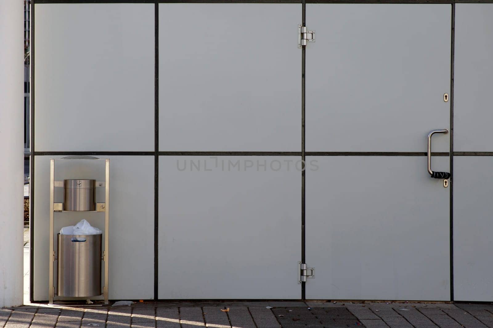 The photograph of a trash can on a modern house wall.