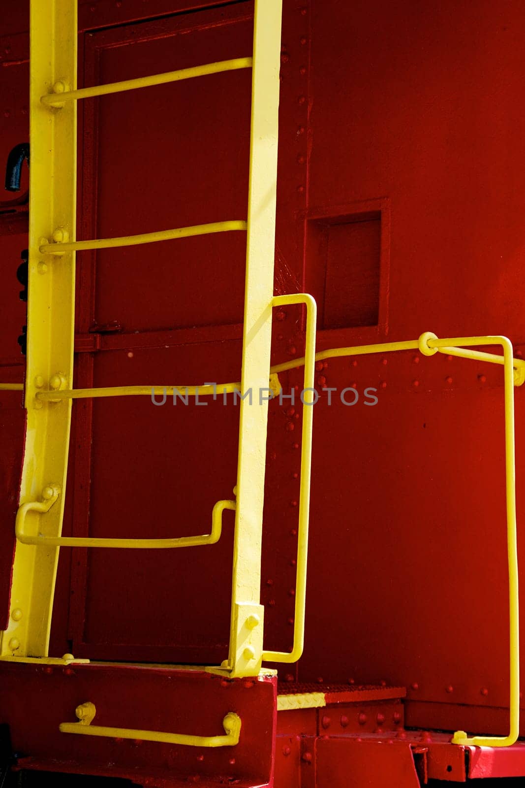 A bright yellow steel ladder on a bright red vintage train caboose.