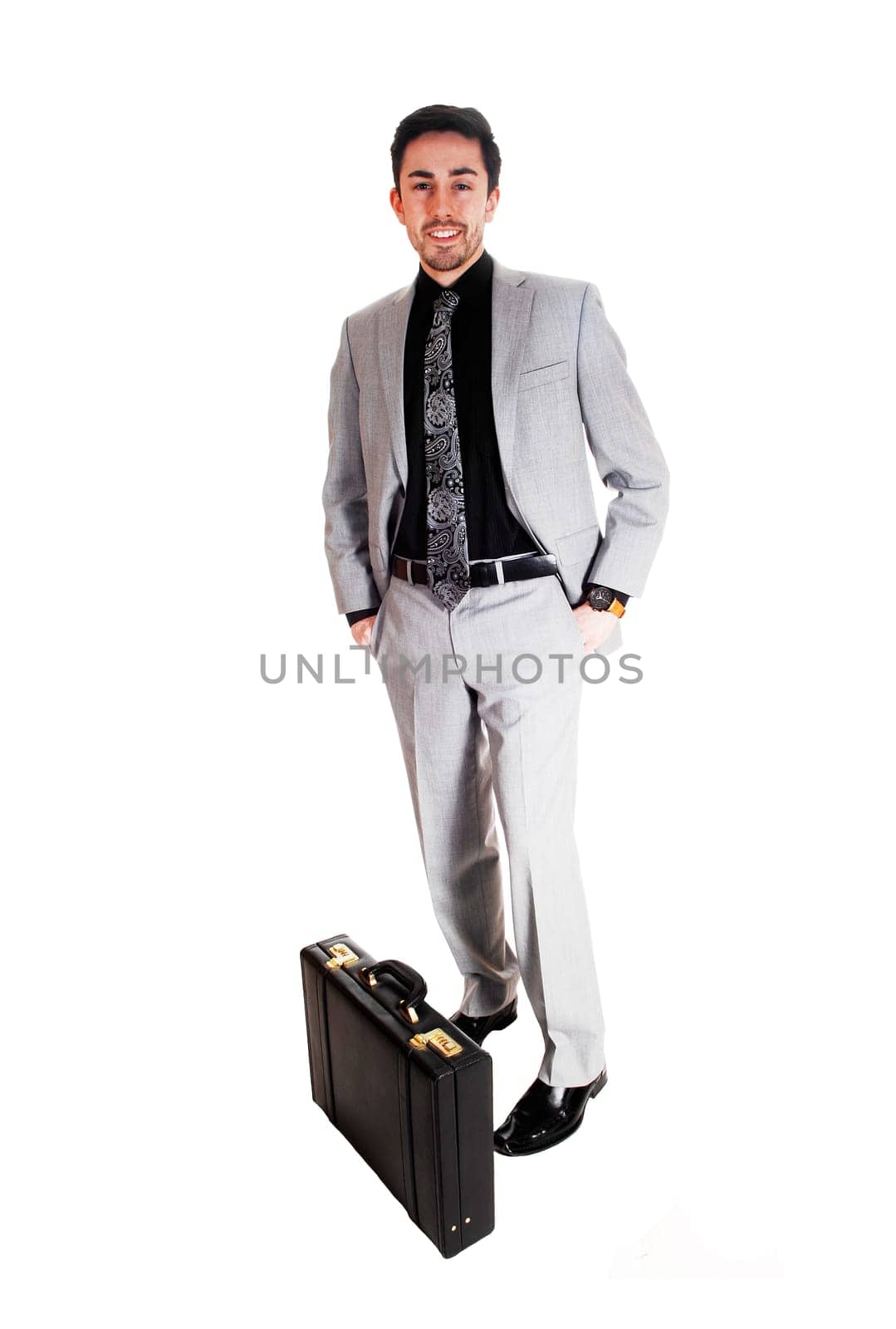 A tall handsome businessman standing for white background in a gray .suit with his briefcase on the floor..