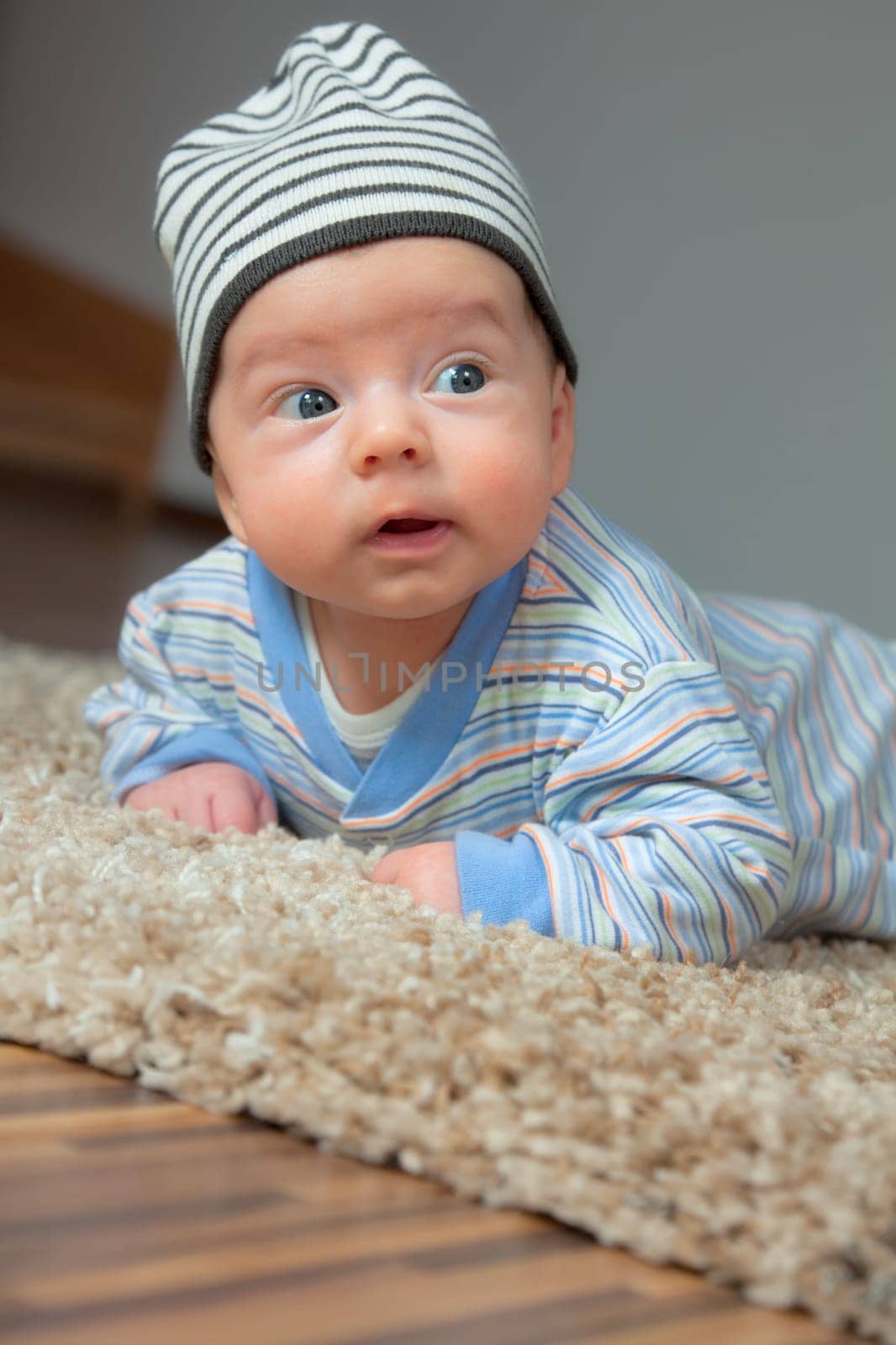 Studio portrait of a happy 2 months old baby boy at home on the floor.