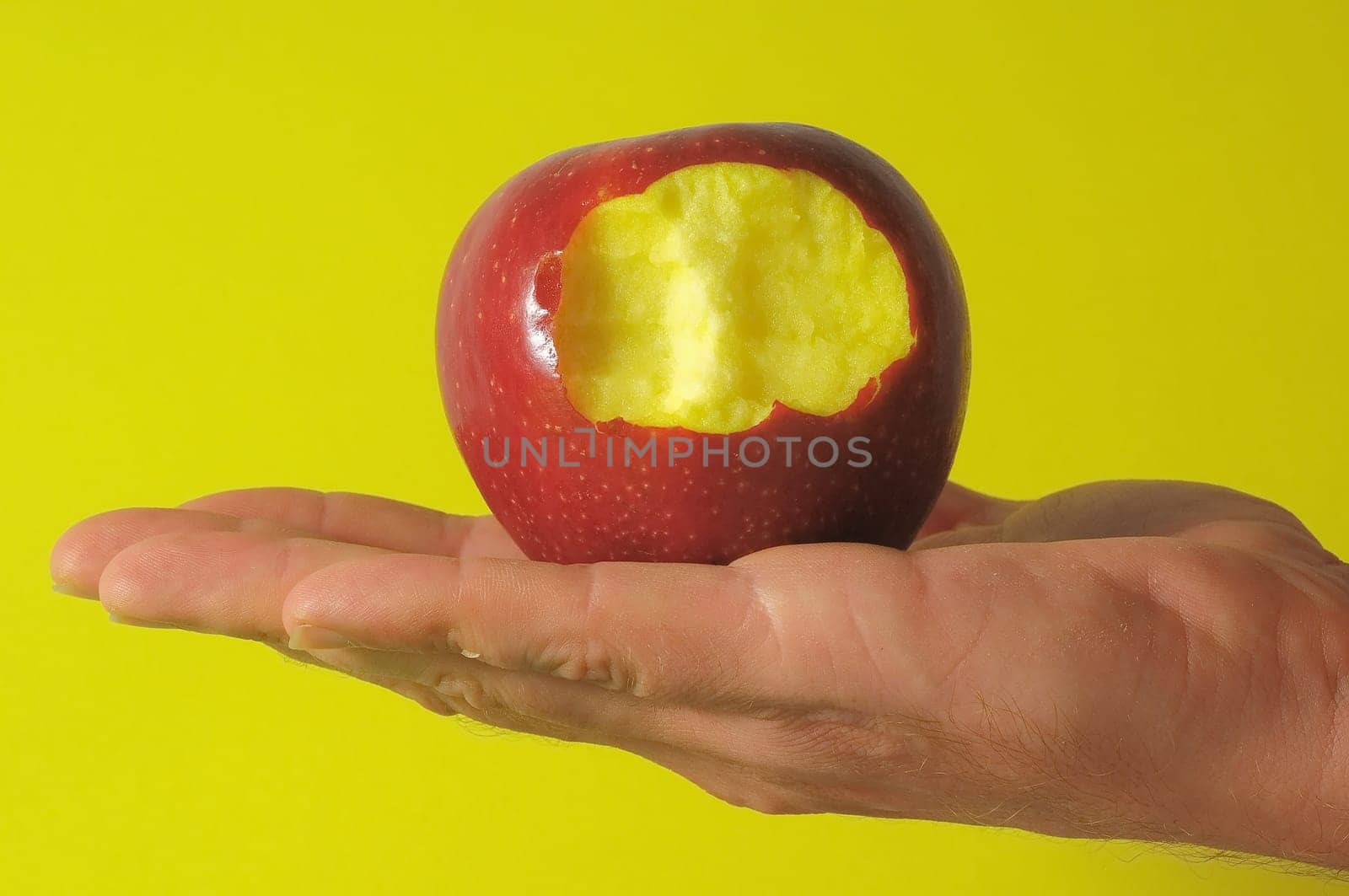 Bitten Red Apple Hand on a Colred Background