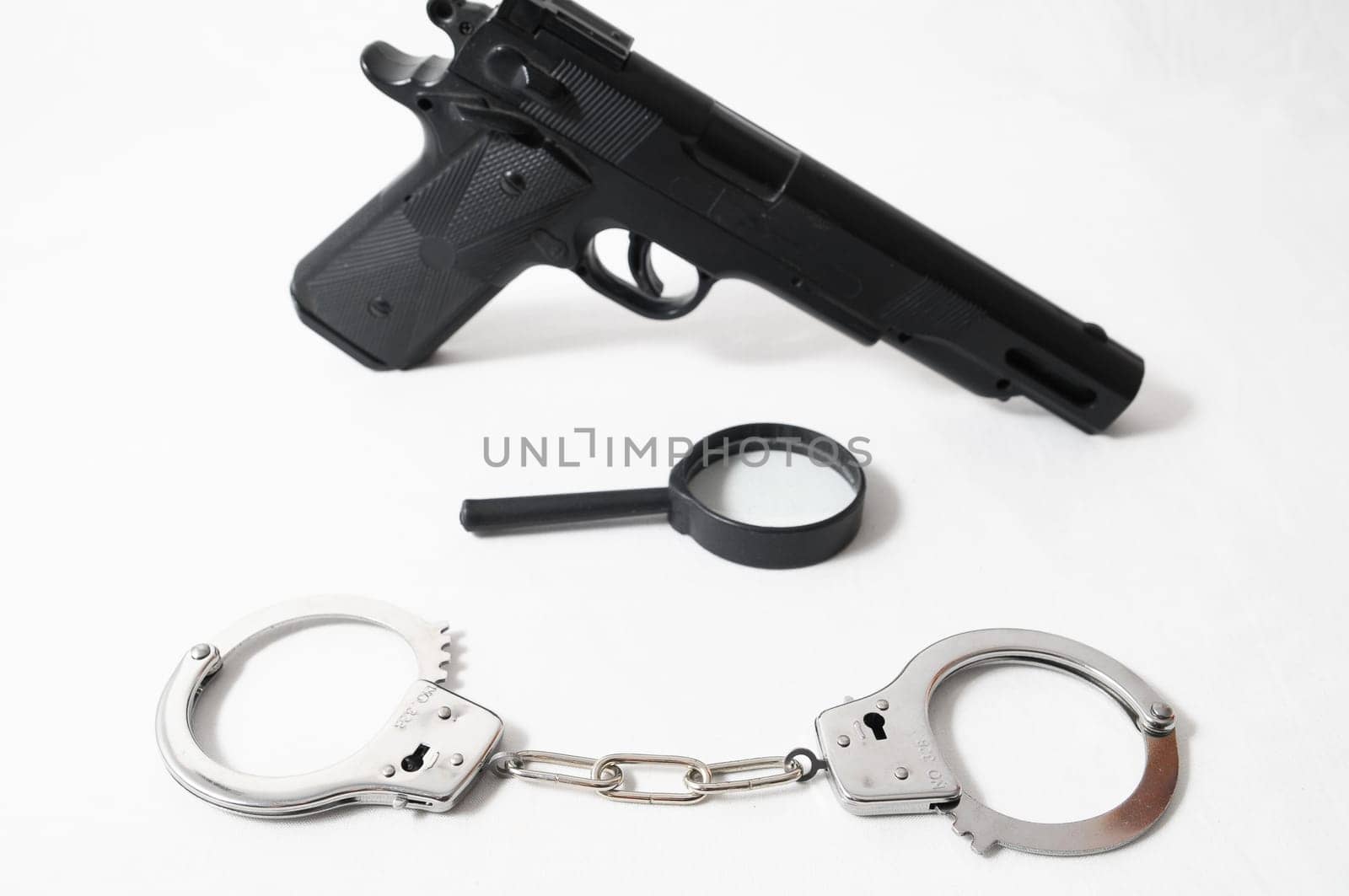 Weapon Crime Concept Gun and Handcuffs on a White Background