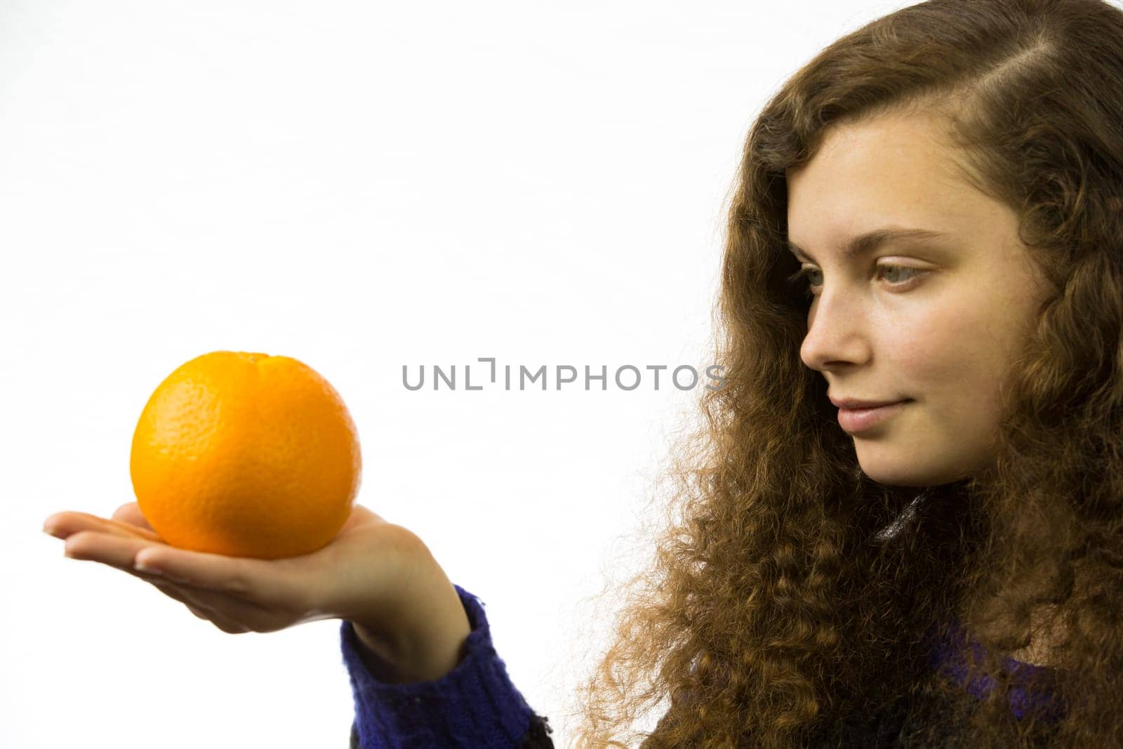 Eine junge hübsche Frau hält eine Orange in der Hand