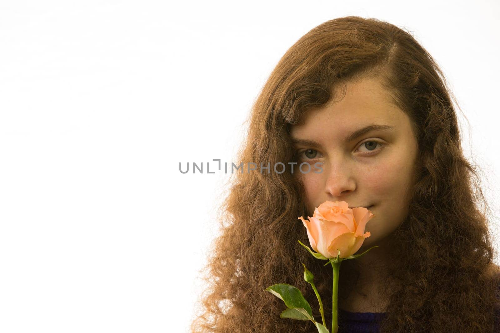 A young pretty woman holds a rose in her hand and smells it