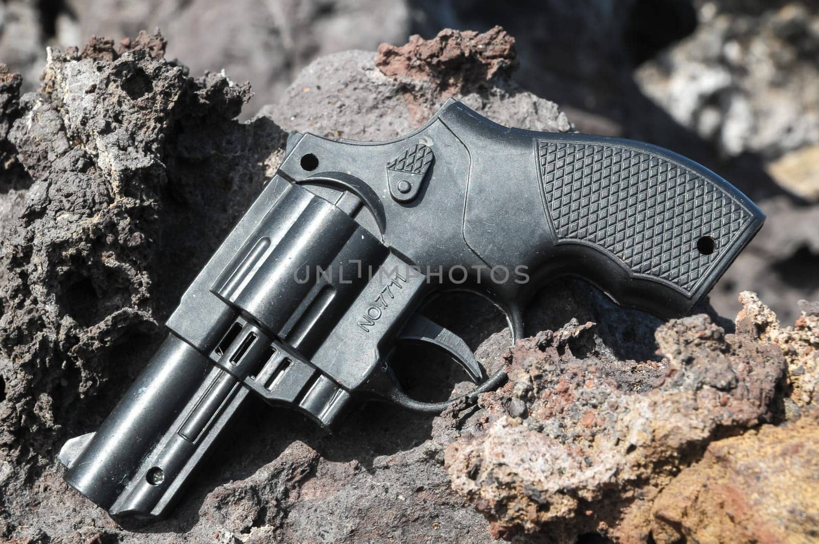 Plastic Revolver Gun Toy on the Volcanic Rocks