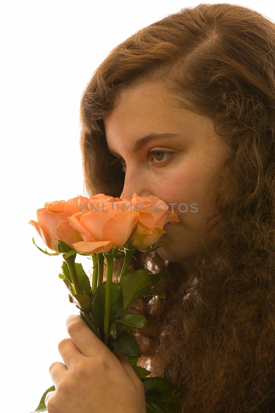 A young pretty woman holds a bouquet of roses in her hand and smells it