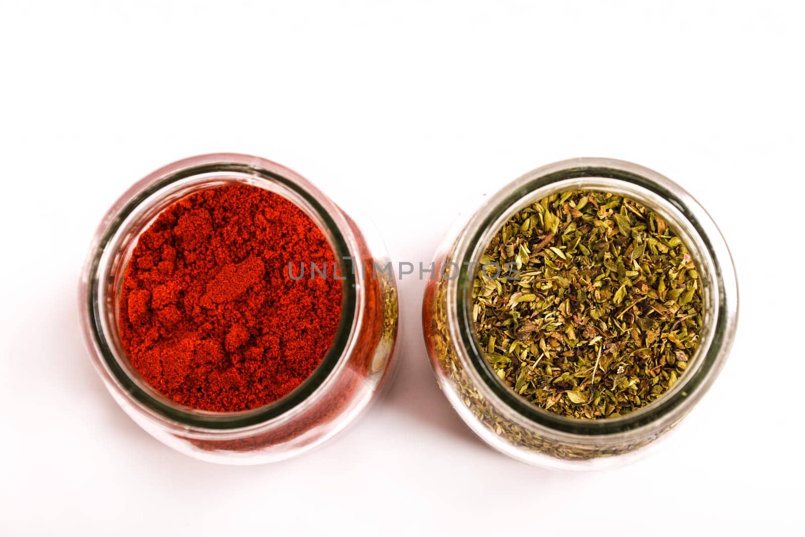 Oregano and paprika powder in a glass pot.