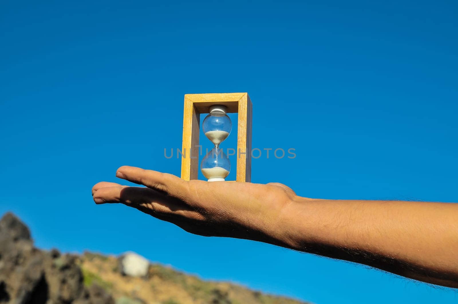 Time Concept White Sand Hourglass on the Volcanic Rocks