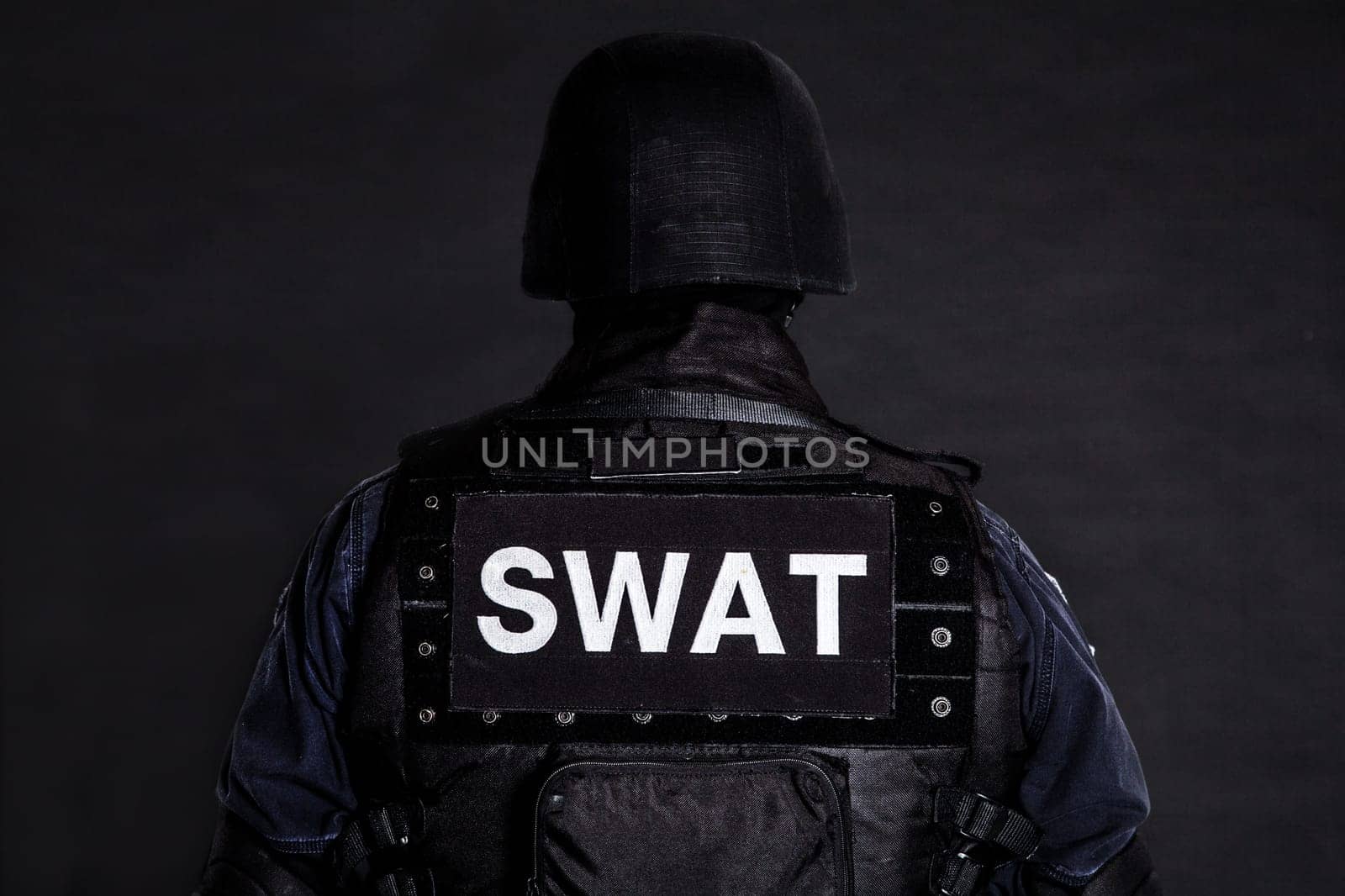 Special weapons and tactics (SWAT) team officer on black background shot from behind