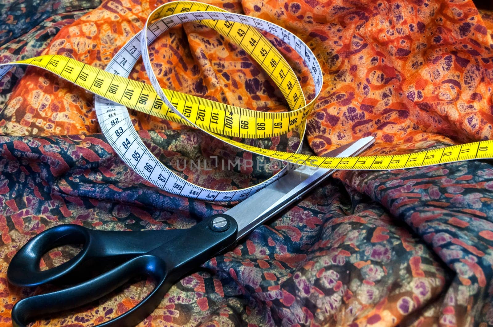 Tailor measuring tape and scissors on patterned fabric