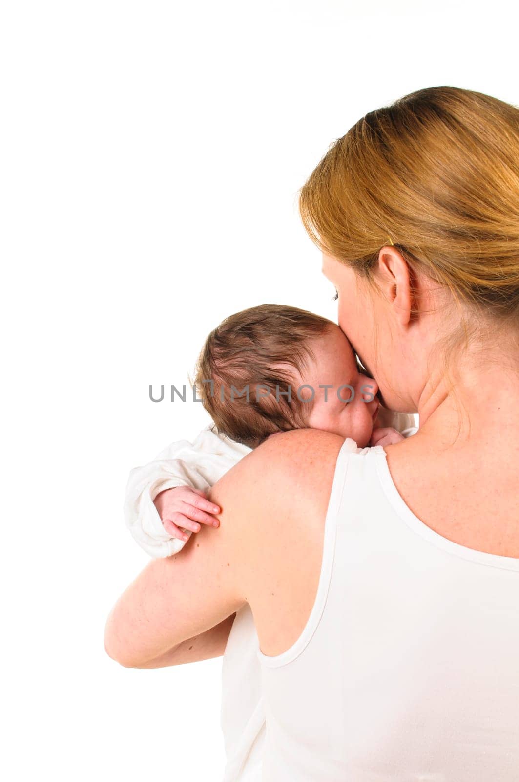An adult woman with a white shirt tenderly holds an infant dressed in white in her arms,exposed against a white background.