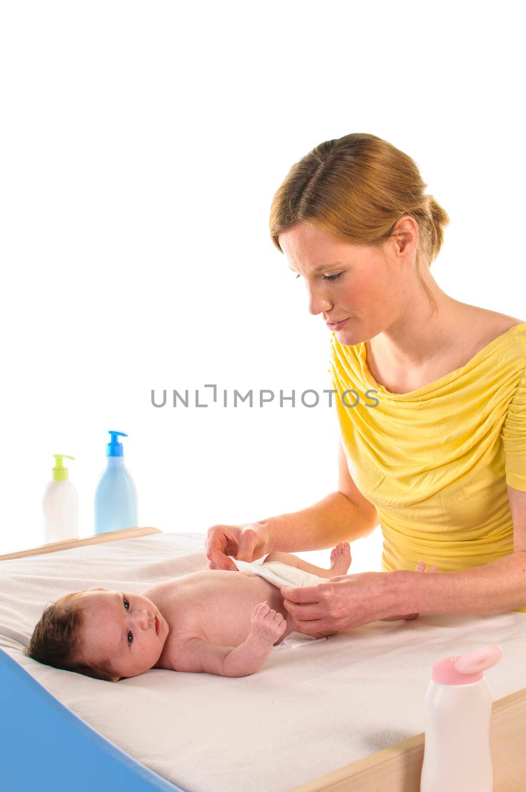Mother with her newborn baby does infant care at the changing table,exposed against a white background.
