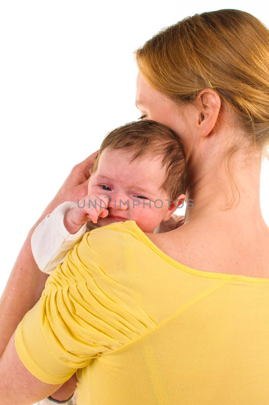 Mother has her newborn baby on her shoulder,the little one rubs her eyes,exposed against a white background.