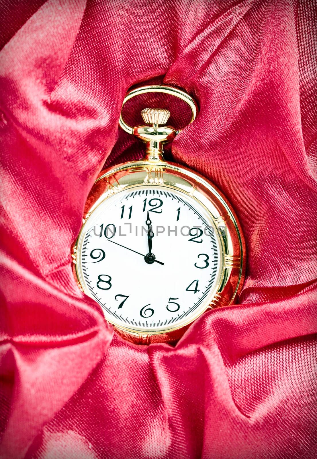 Old styled gold pocket watch on scarlet silk