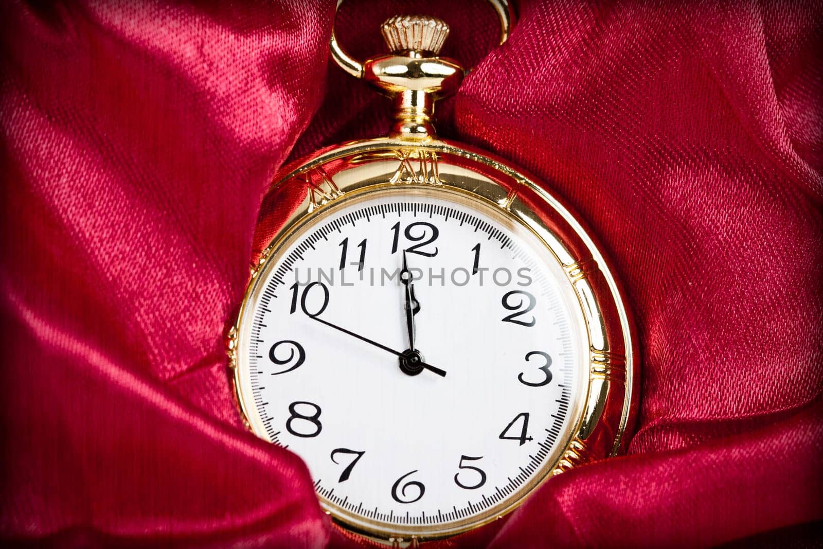 Old styled gold pocket watch on scarlet silk