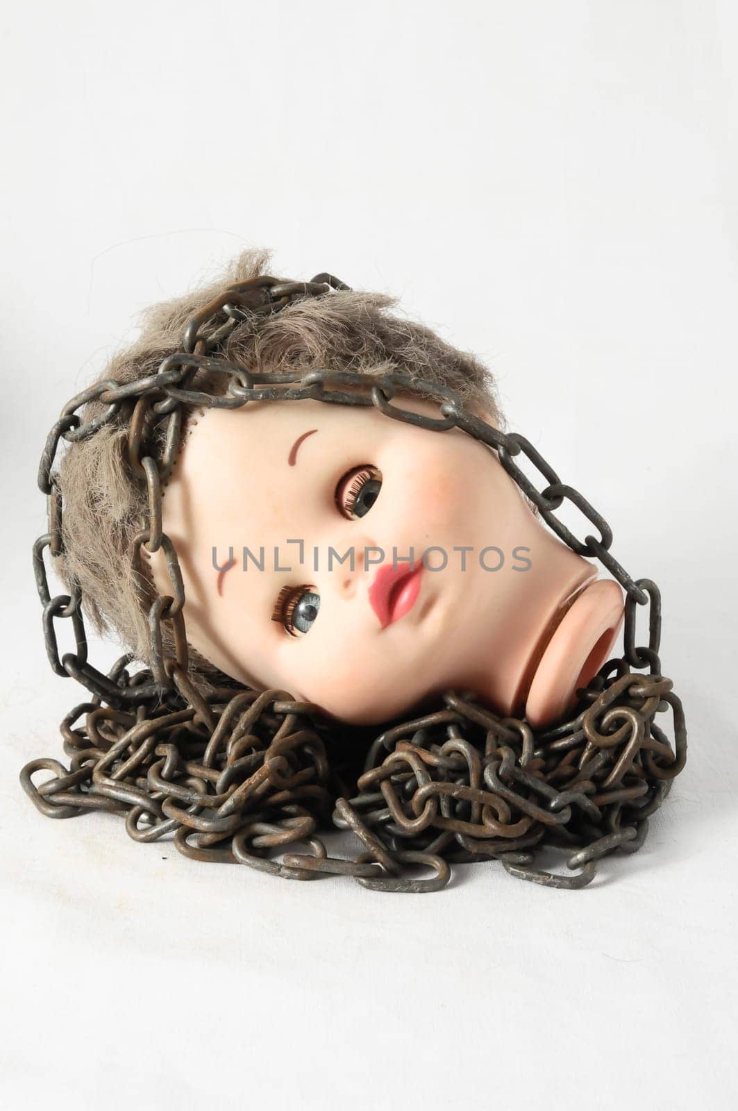 Vintage Plastic Scary Doll Head and Chain on a White Background