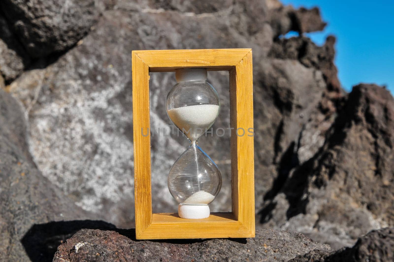 Time Concept White Sand Hourglass on the Volcanic Rocks
