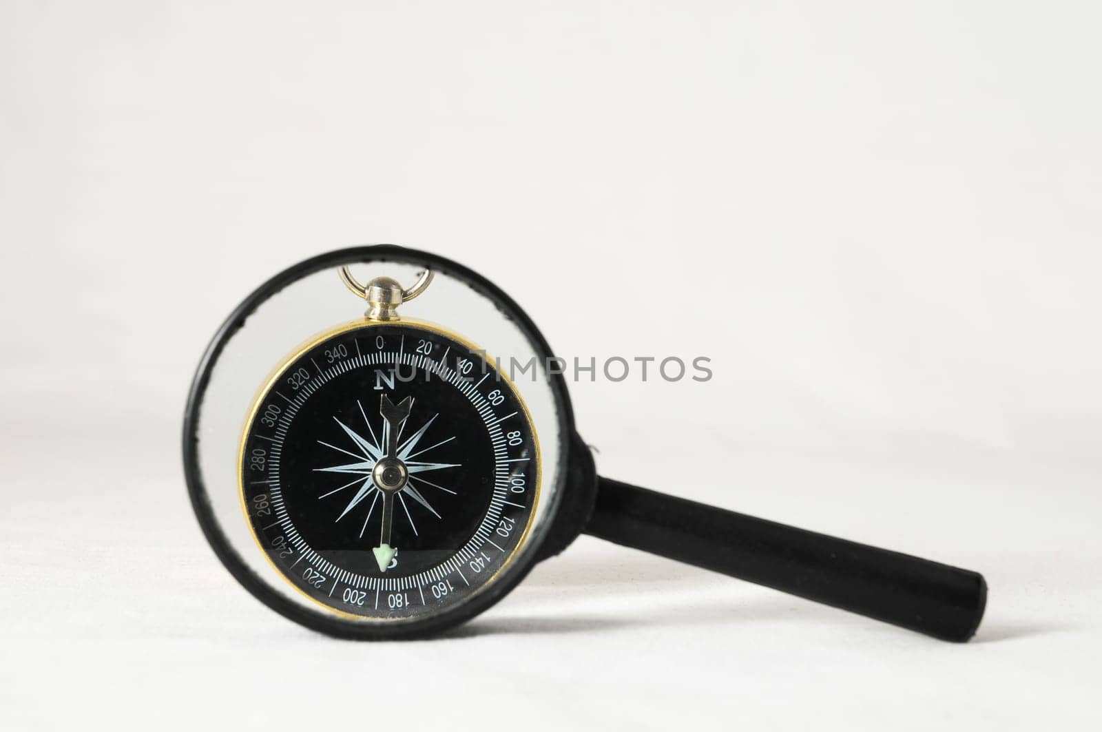 Orientation Concept - Analogic Compass and Loupe on a White Background