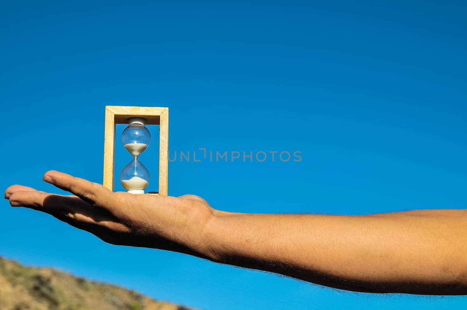Time Concept White Sand Hourglass on the Volcanic Rocks